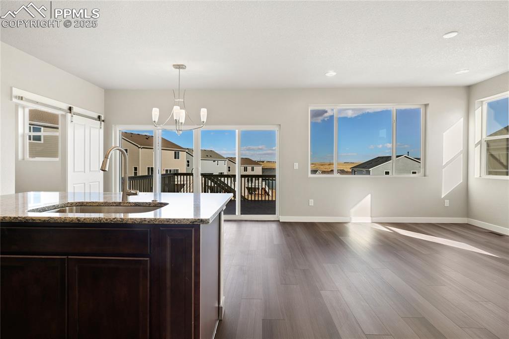 Image 10 of 38: Kitchen with dark brown cabinetry, light stone countertops, healthy amount