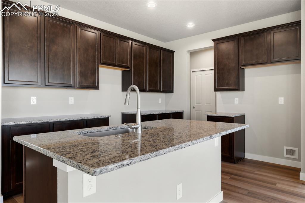 Image 11 of 38: Kitchen featuring light stone countertops, light wood-type flooring, a cent