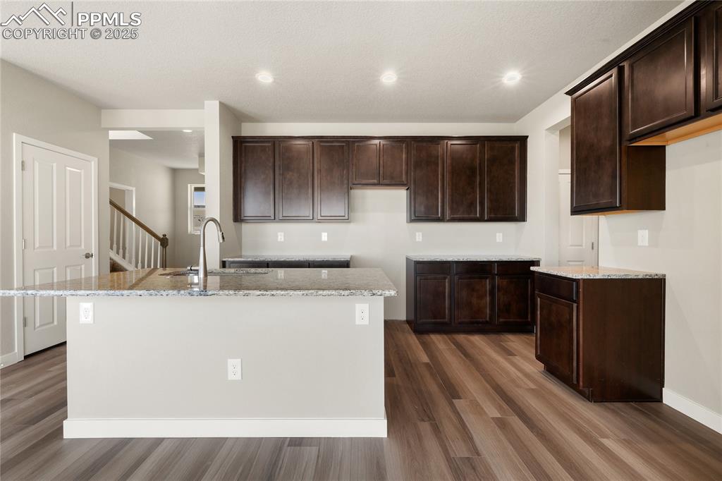 Image 12 of 38: Kitchen featuring light stone countertops, a center island with sink, reces