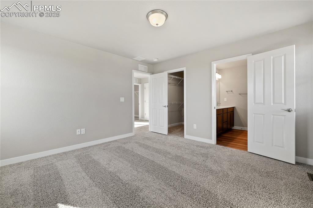 Image 32 of 38: Unfurnished bedroom with carpet flooring, a walk in closet, and ensuite bat