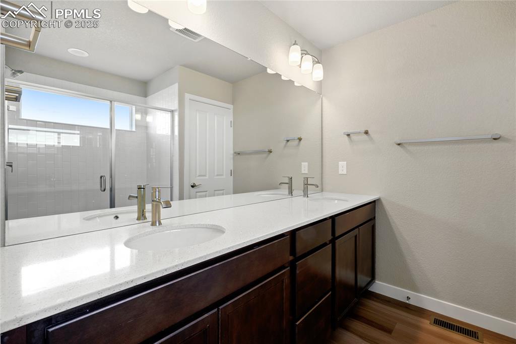 Image 34 of 38: Bathroom featuring a shower stall, and double vanity