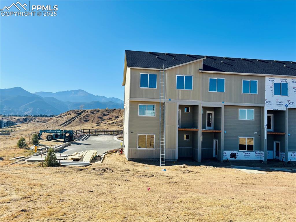 Image 4 of 16: Back of house with a shingled roof and a mountain view