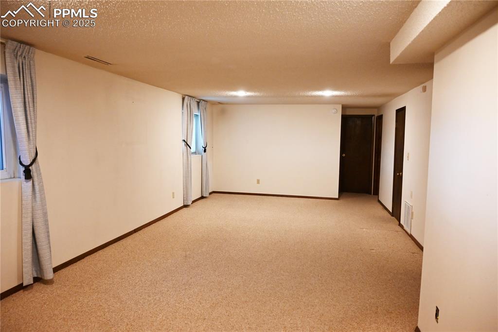 Image 12 of 17: Empty room featuring light colored carpet and a textured ceiling