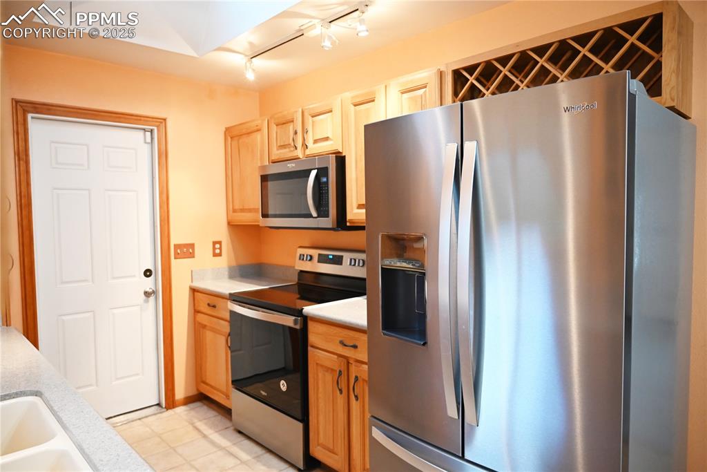 Image 15 of 17: Kitchen with appliances with stainless steel finishes, light countertops, a