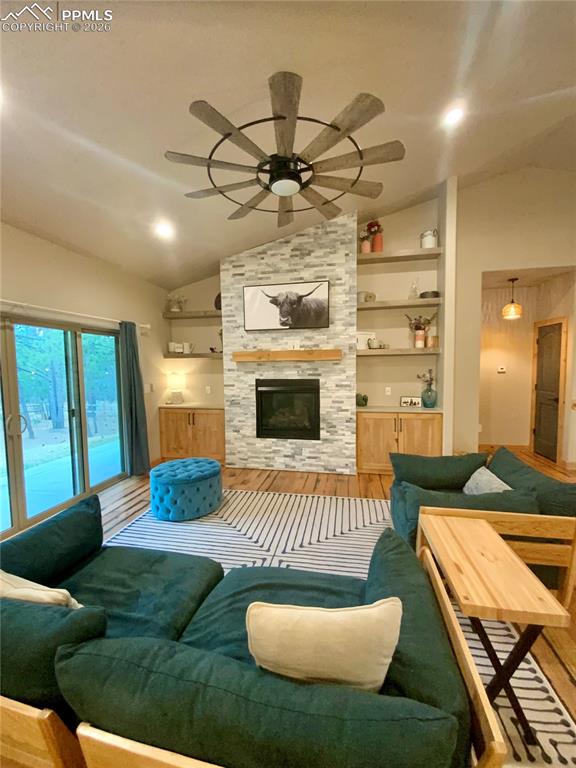 Image 10 of 47: Living area featuring vaulted ceiling, wood floors, ceiling fan, built in f