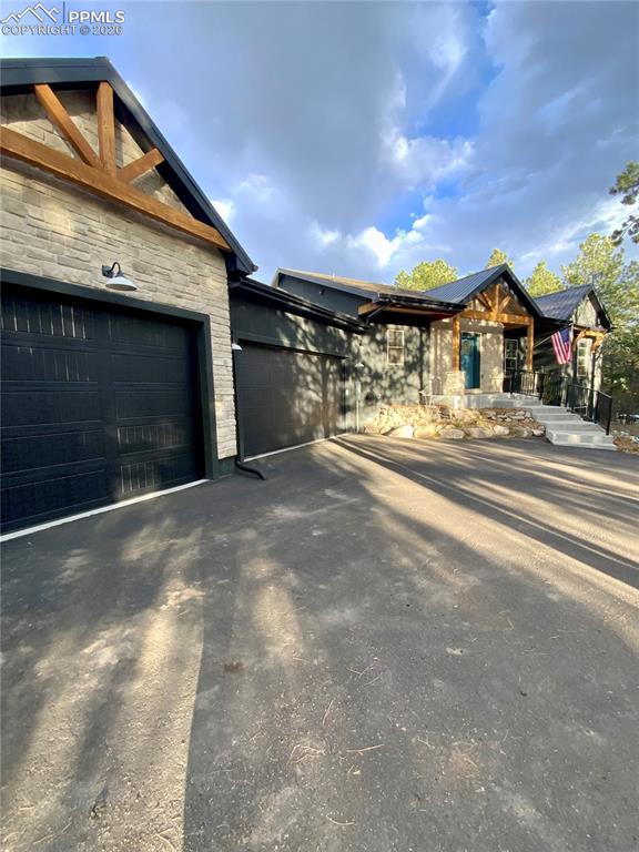 Image 2 of 47: View of side of home with stone accents, asphalt driveway, and an attached 