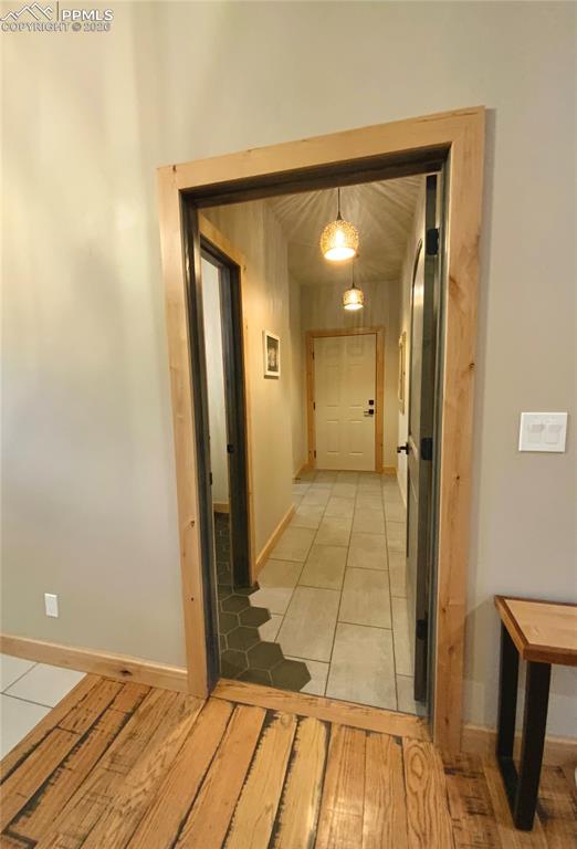 Image 21 of 47: Hall leading to three car garage with unique transition from tile to hardwo