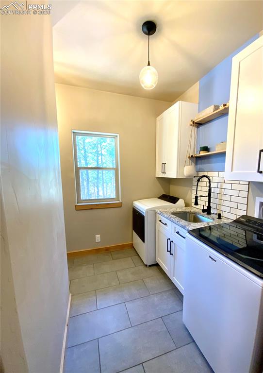 Image 23 of 47: Laundry room with white cabinetry, open shelves, decorative backsplash, and