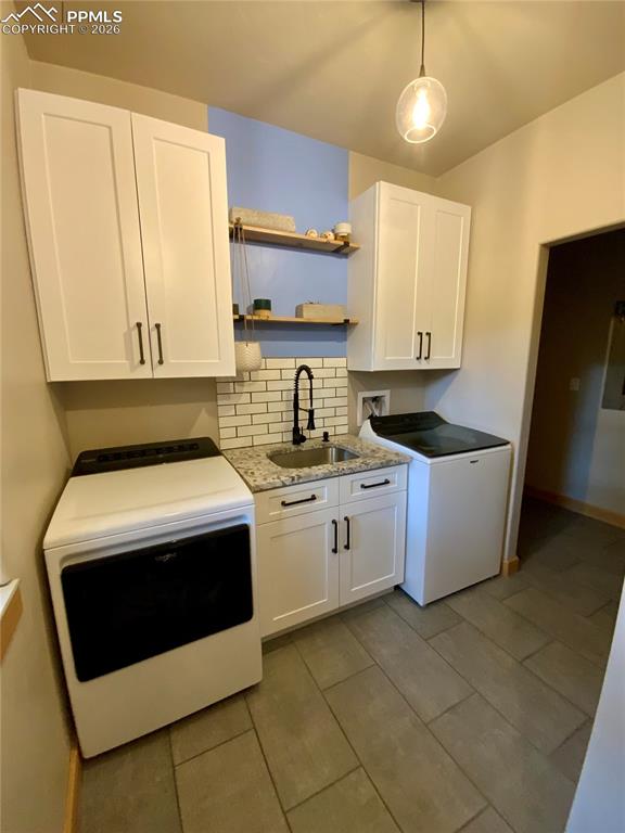 Image 24 of 47: Laundry room featuring decorative backsplash, white cabinetry, light stone 