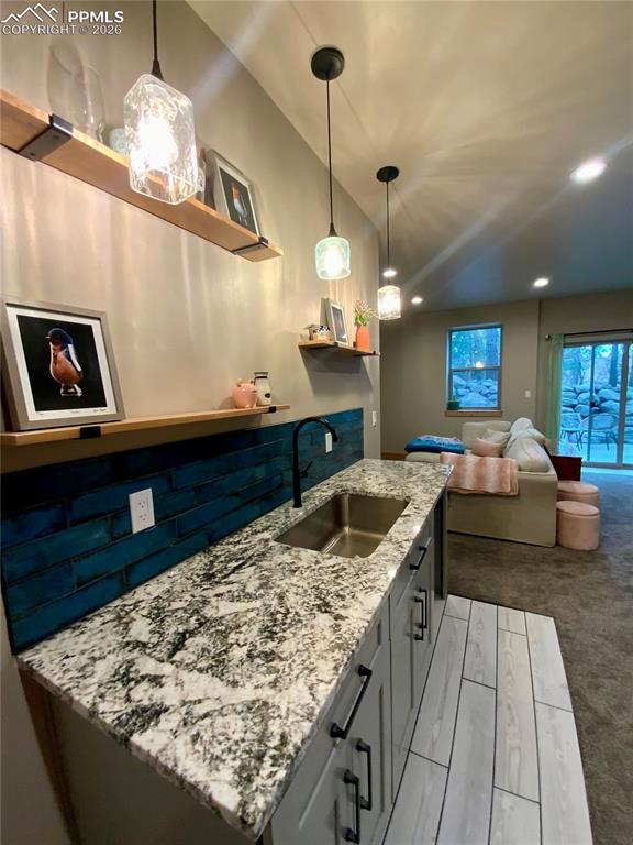 Image 29 of 47: Wet bar featuring open shelves, granite countertops, custom pendant lightin