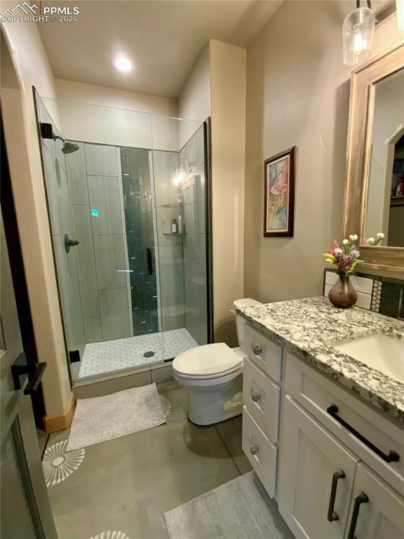 Image 31 of 47: Ensuite bathroom featuring vanity, a stall shower, and concrete floors