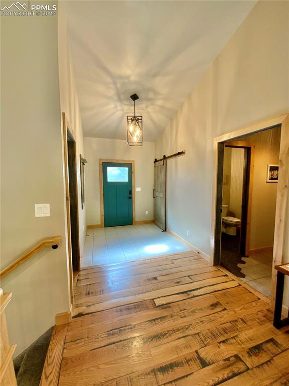 Image 5 of 47: Foyer featuring a barn door and both tile and wood floors