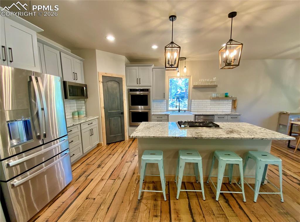 Image 6 of 47: Kitchen with stainless steel appliances, a kitchen island with gas cooktop,
