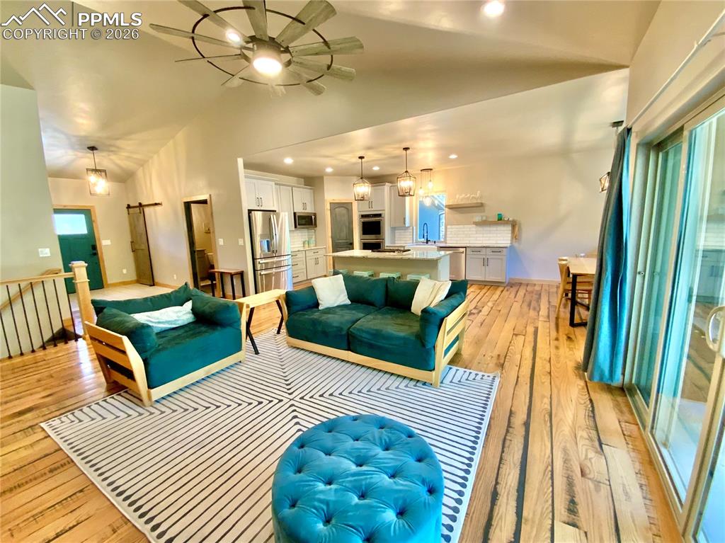 Image 8 of 47: Living room with vaulted ceiling, wood flooring, a ceiling fan, recessed li