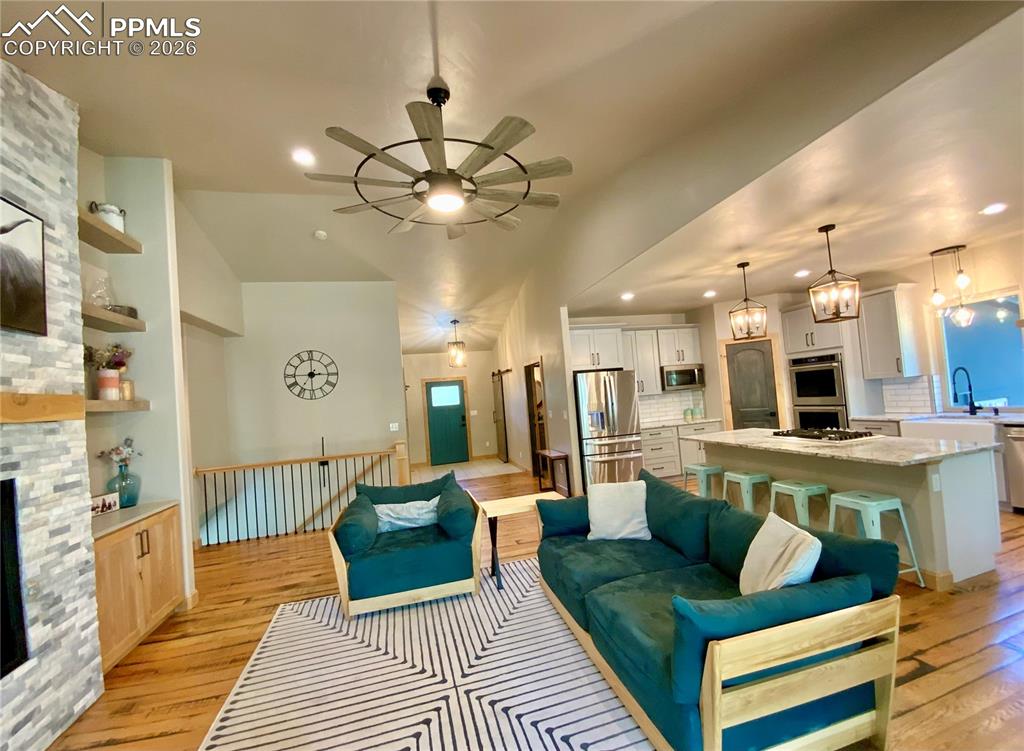 Image 9 of 47: Open concept living room featuring rustic wood floors, ceiling fan, and a s