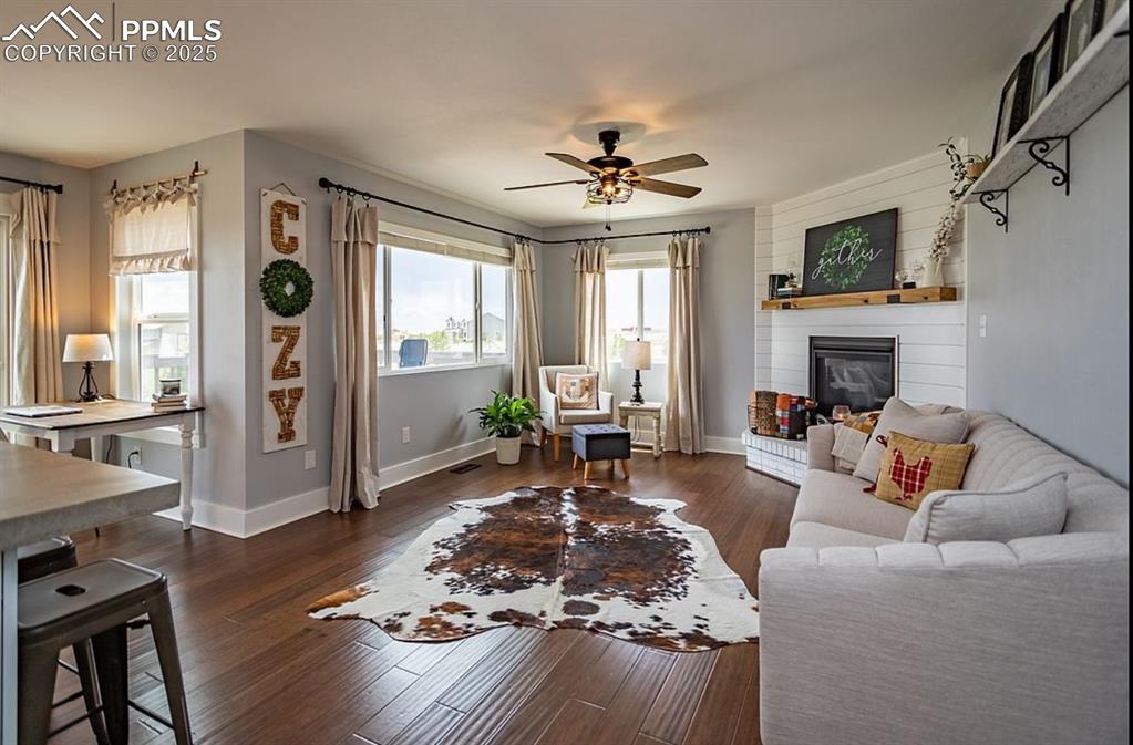 Image 13 of 44: Living room with dark wood-type flooring, a large fireplace, and ceiling fa