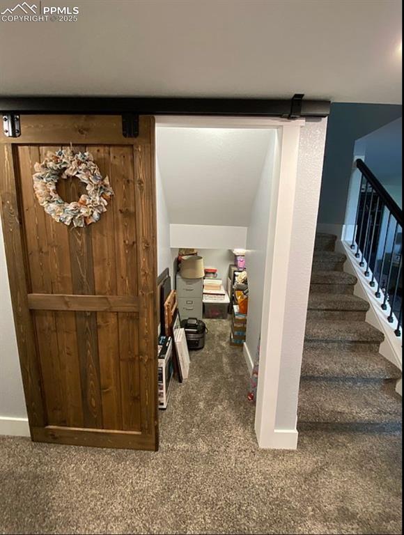 Image 27 of 44: Stairway with a barn door and carpet flooring
