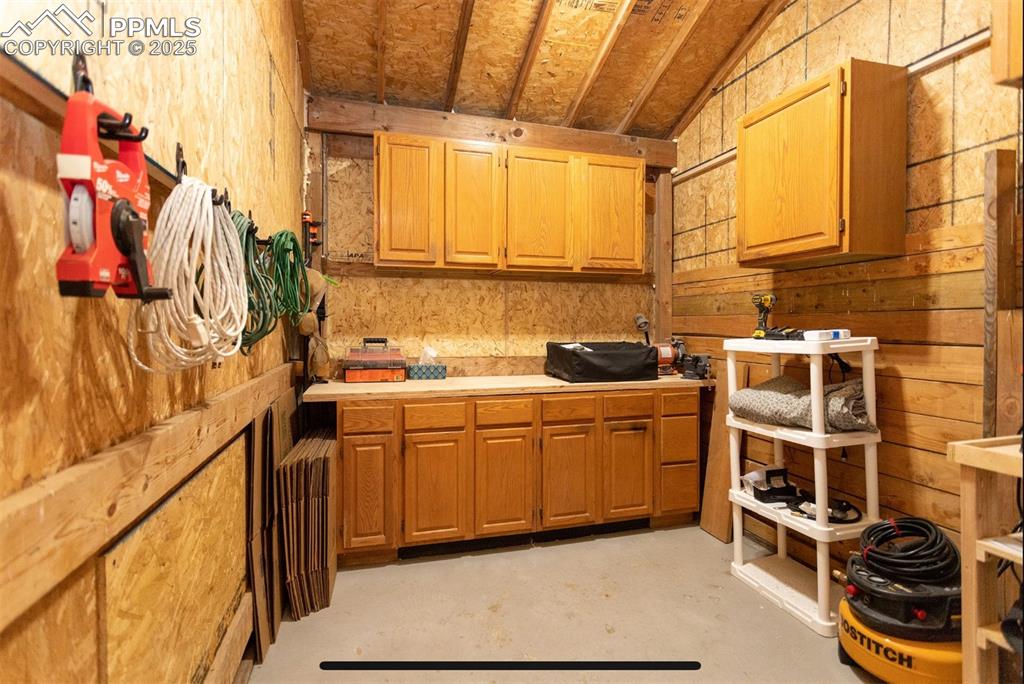 Image 40 of 44: Kitchen with light countertops, concrete floors, lofted ceiling, brown cabi