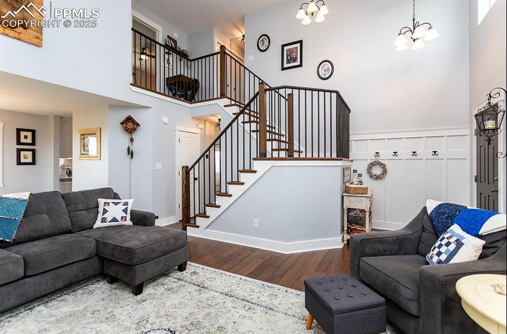 Image 5 of 44: Living room featuring a high ceiling, wood finished floors, a chandelier, a