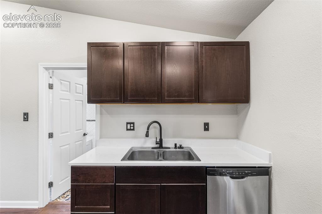 Image 10 of 32: Dark wood cabinetry, white countertops, double-basin stainless steel sink, 
