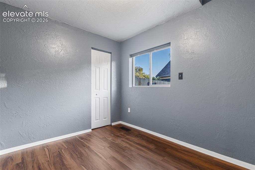 Image 14 of 32: Interior room featuring wood-finish flooring, grey textured walls, and a si