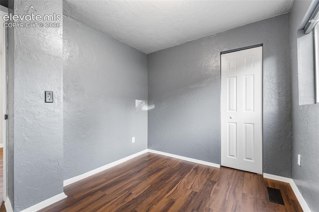 Image 15 of 32: Interior room featuring textured grey walls, wood-finish flooring, and a wh