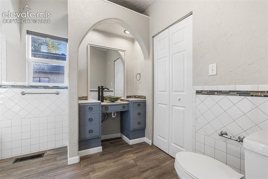 Image 16 of 32: Bathroom featuring a decorative architectural arch, custom blue vanity with
