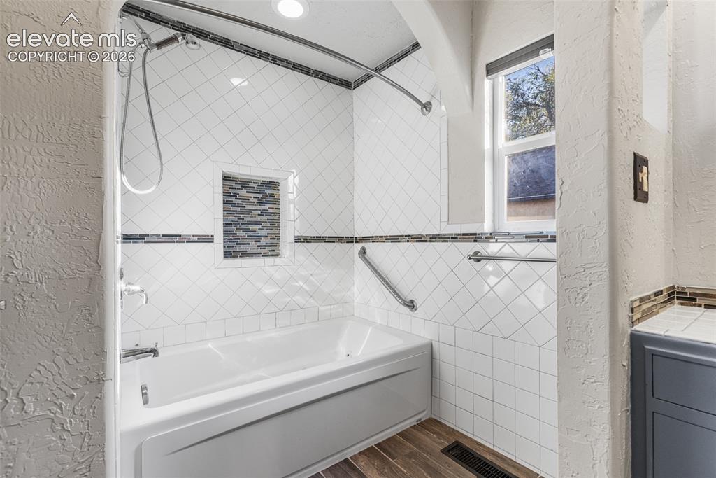 Image 17 of 32: Bathtub enclosure featuring white diamond-pattern tile walls, a decorative 