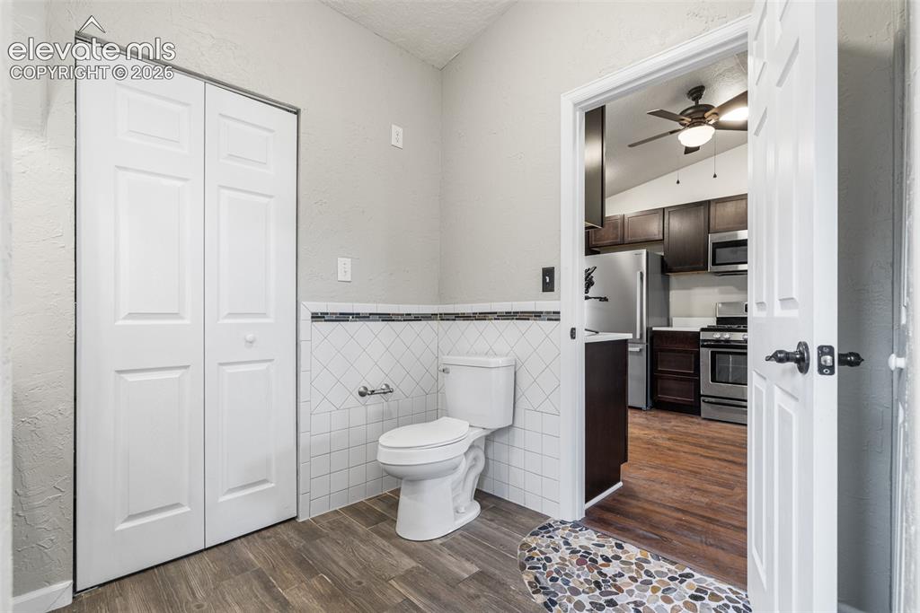 Image 19 of 32: Restroom featuring wood-finish flooring, white diamond-pattern wall tile wi