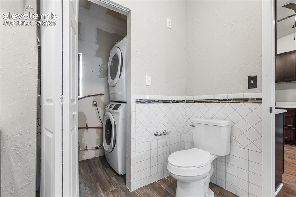 Image 20 of 32: Bifold closet doors, stacked front-load laundry appliances, white wall-moun