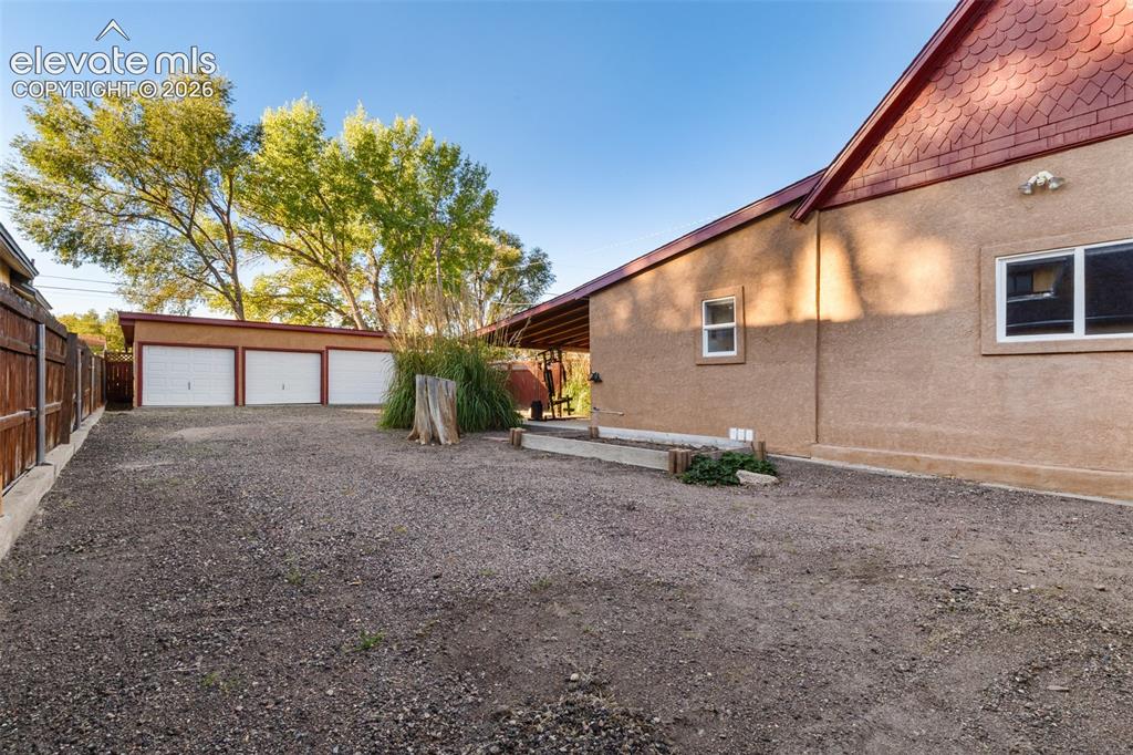 Image 22 of 32: Exterior featuring a three-car detached garage, stucco siding, shingle roof