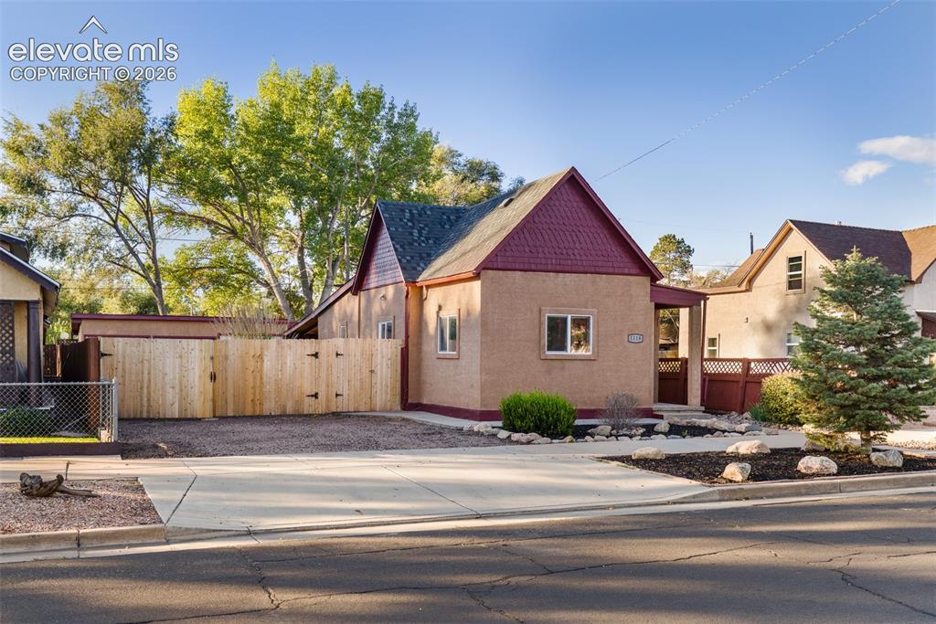 Image 4 of 32: Stucco exterior with shingle-pattern gable siding, concrete driveway, and w