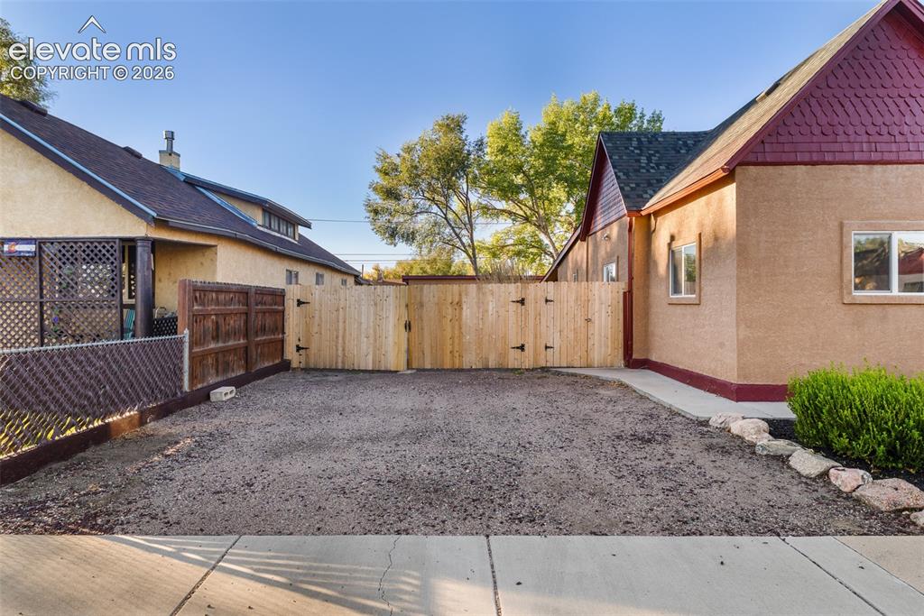 Image 5 of 32: Stucco exterior featuring textured siding, wood-style trim, and a fenced-in