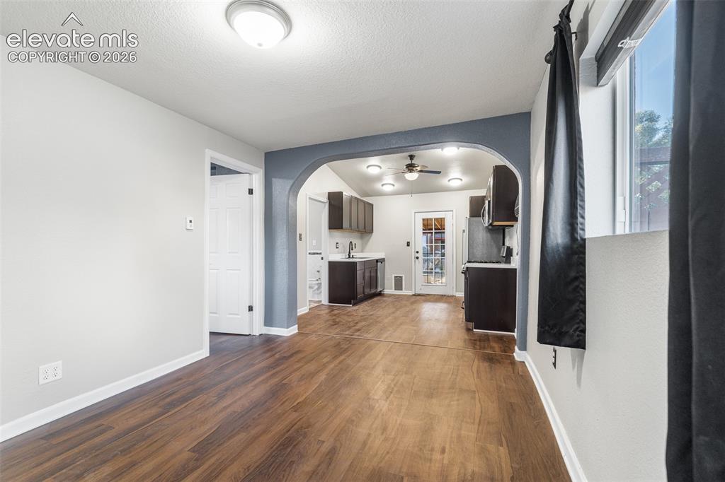 Image 6 of 32: Interior space featuring an arched entryway, wood-finish flooring, dark-ton