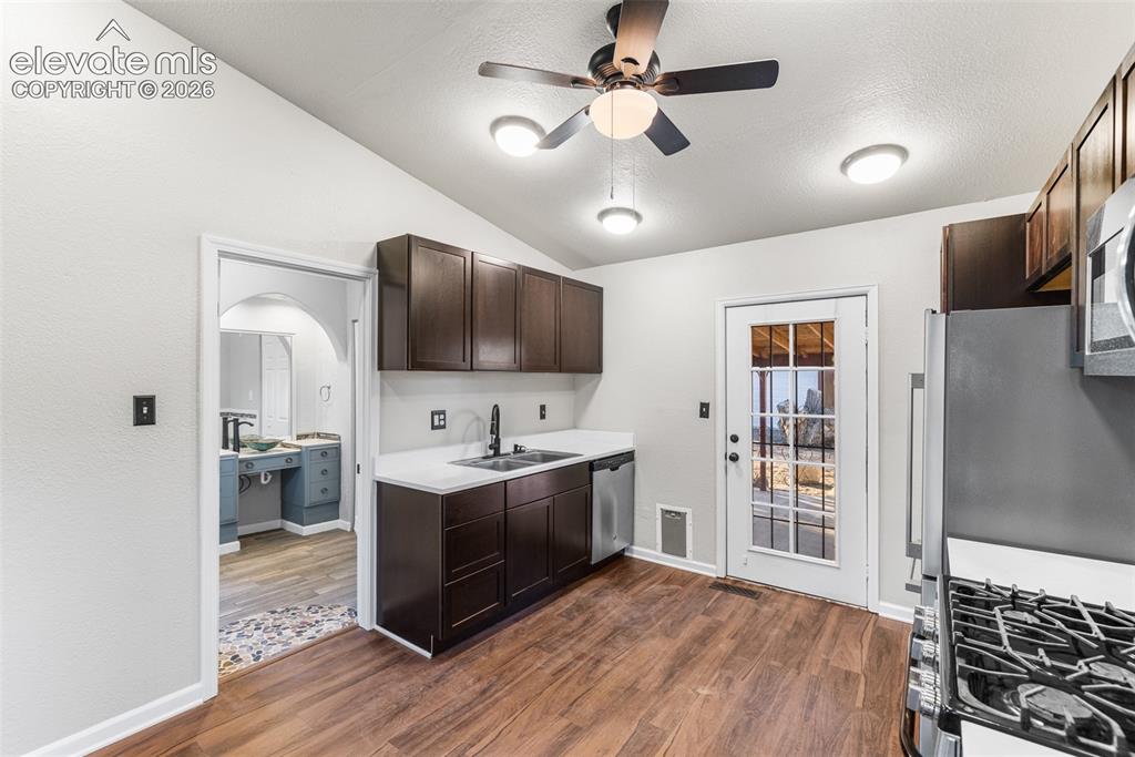 Image 8 of 32: Kitchen featuring dark wood cabinetry, contrasting light-toned countertops,