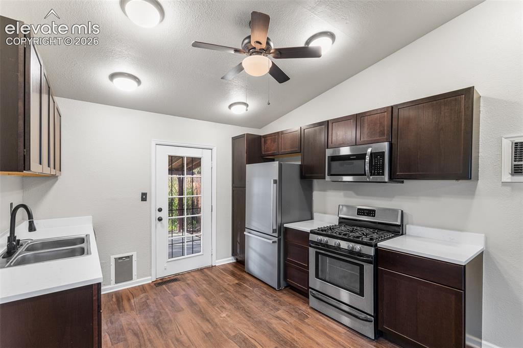 Image 9 of 32: Kitchen featuring dark-finish cabinetry, solid-surface countertops, stainle