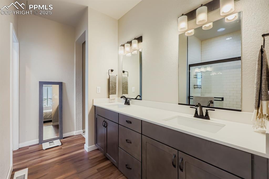 Image 13 of 28: Full bath featuring double vanity, dark wood finished floors, a shower stal