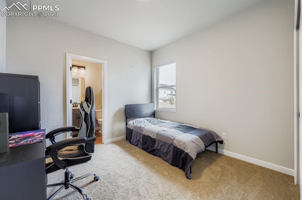 Image 16 of 28: Bedroom with carpet flooring, ensuite bathroom, and a desk
