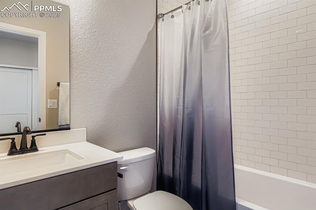 Image 17 of 28: Full bathroom featuring a textured wall, vanity, and shower / bathtub combi