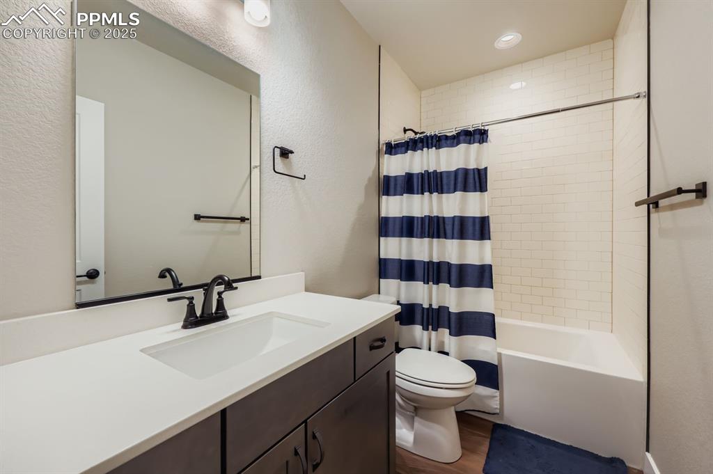 Image 21 of 28: Bathroom with dark wood-type flooring, a textured wall, shower / tub combo 