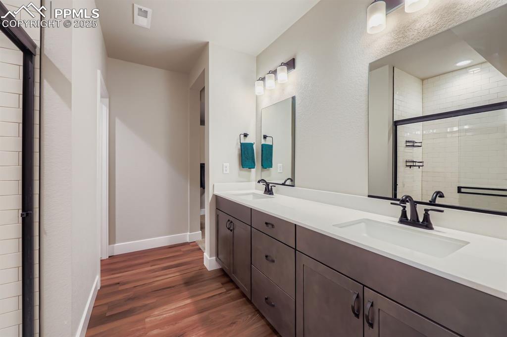 Image 23 of 28: Full bath featuring a stall shower, double vanity, and dark wood-type floor