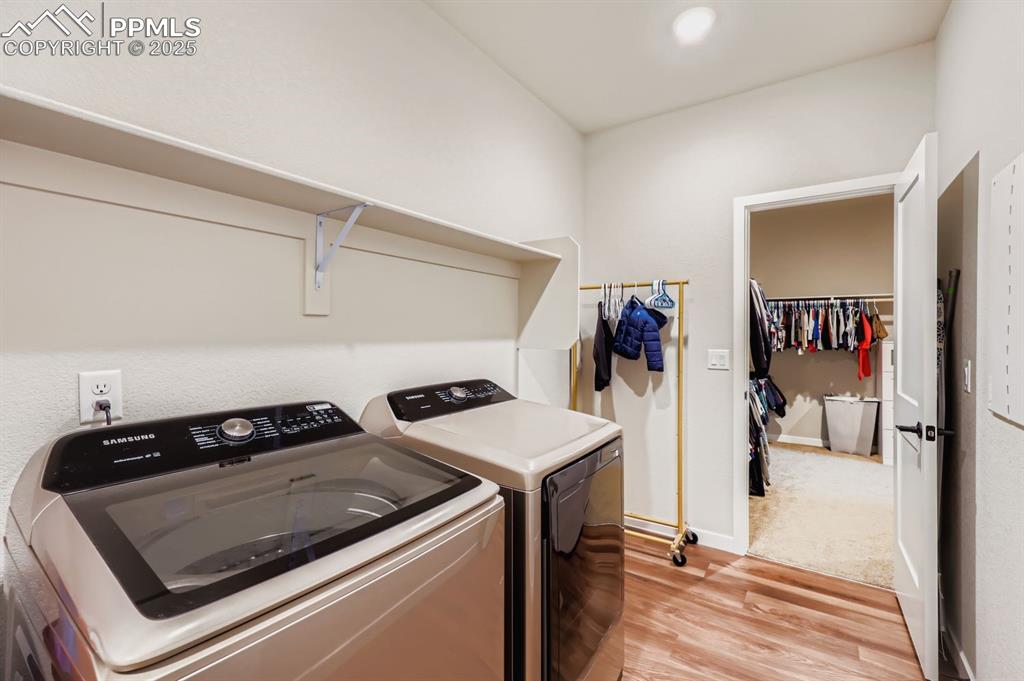 Image 26 of 28: Laundry area with light wood finished floors and independent washer and dry