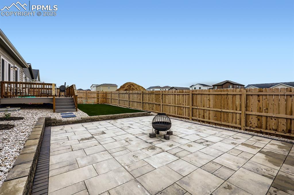 Image 27 of 28: Fenced backyard with a residential view, an outdoor fire pit, a deck, and a