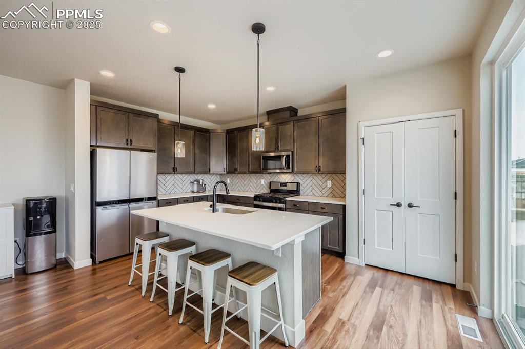 Image 7 of 28: Kitchen featuring stainless steel appliances, a breakfast bar area, pendant
