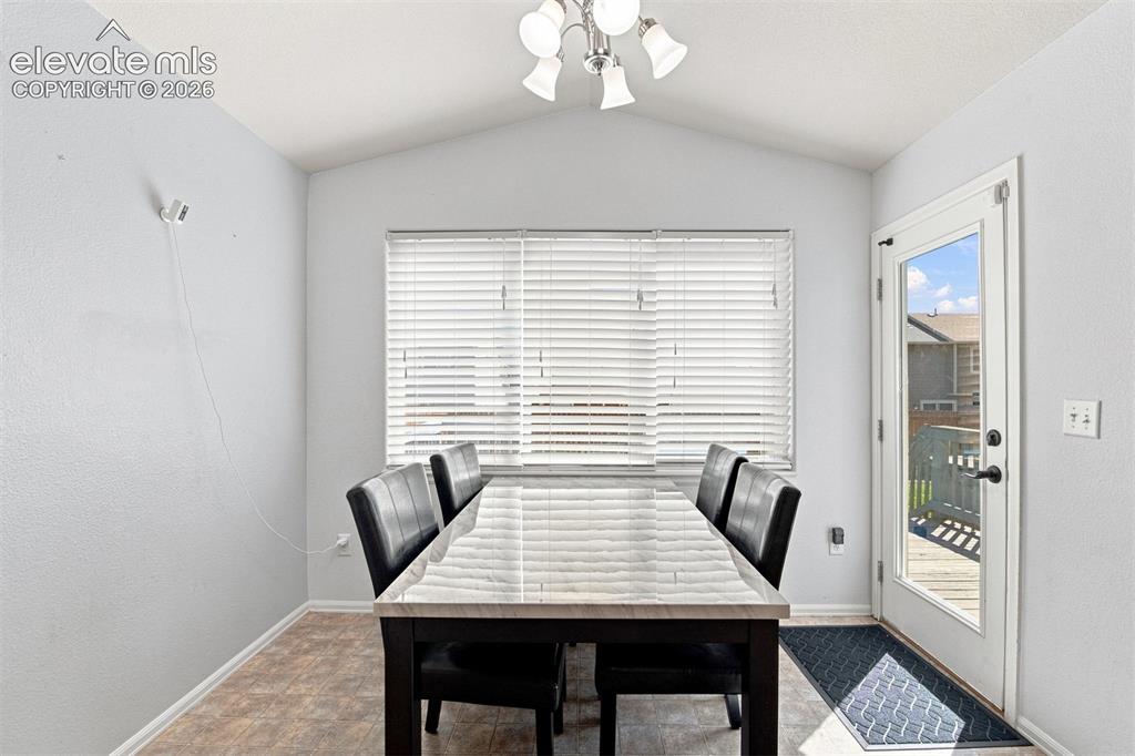 Image 12 of 32: Vaulted ceiling with an attached light fixture, a large window with blinds,