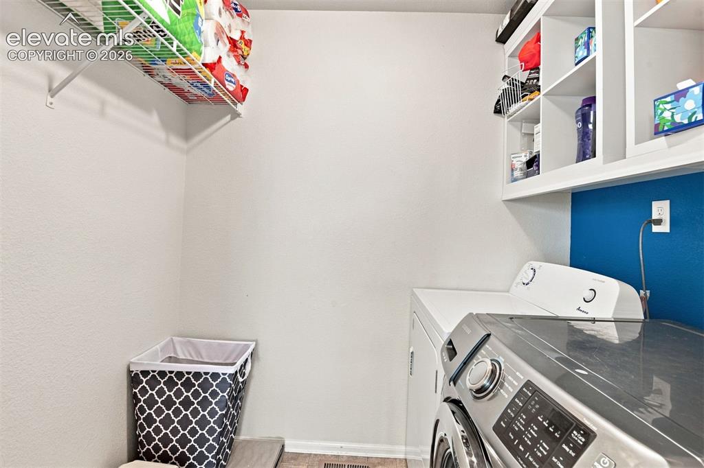 Image 16 of 32: Laundry area featuring white walls, open shelving, and a wire rack