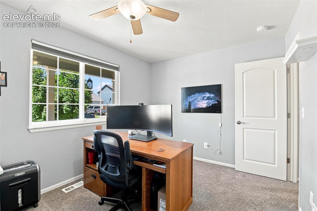 Image 18 of 32: White paneled interior door, window with gridded panes, and a ceiling fan w