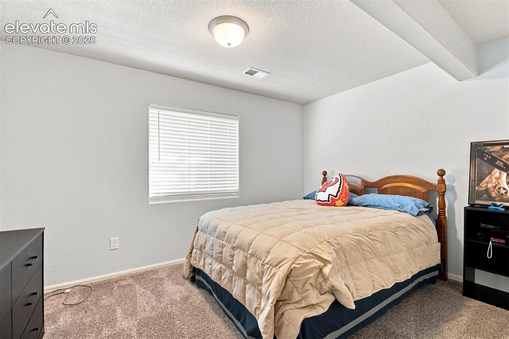 Image 25 of 32: Recessed ceiling with exposed beam, wall-mounted light fixture, window with