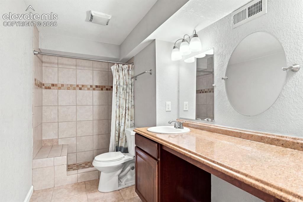 Image 27 of 32: Bathroom featuring a tiled shower with integrated bench, a single vanity wi