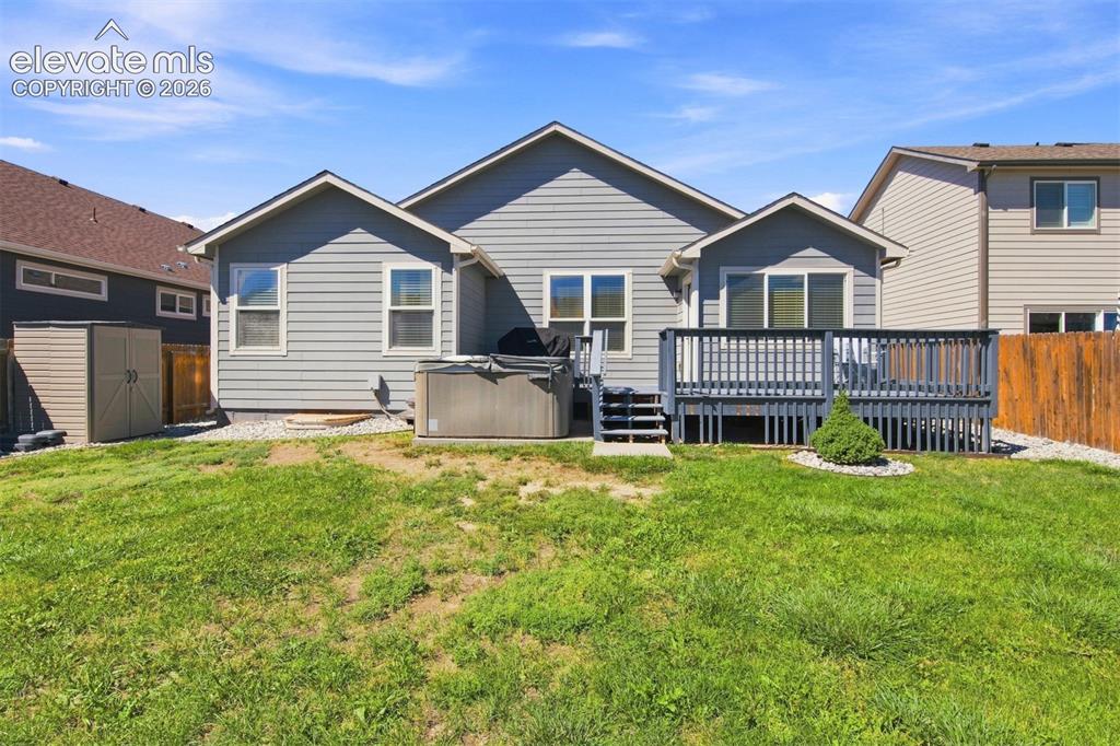 Image 32 of 32: Rear exterior featuring a large elevated deck, multiple windows, a hot tub,